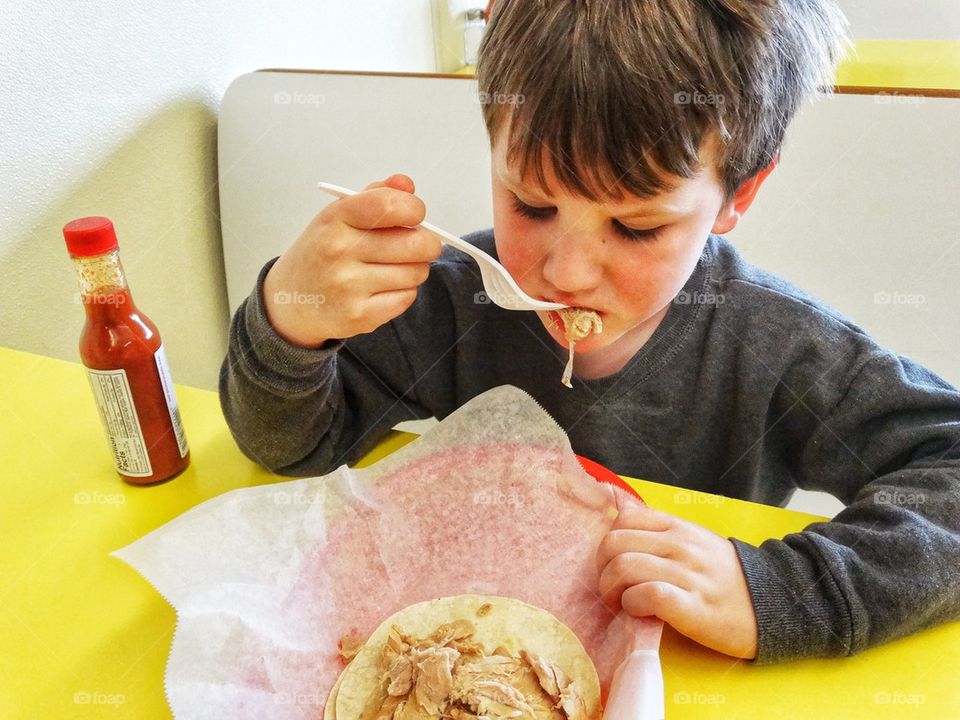 Young Boy Eating Lunch. Little Boy Using Utensils
