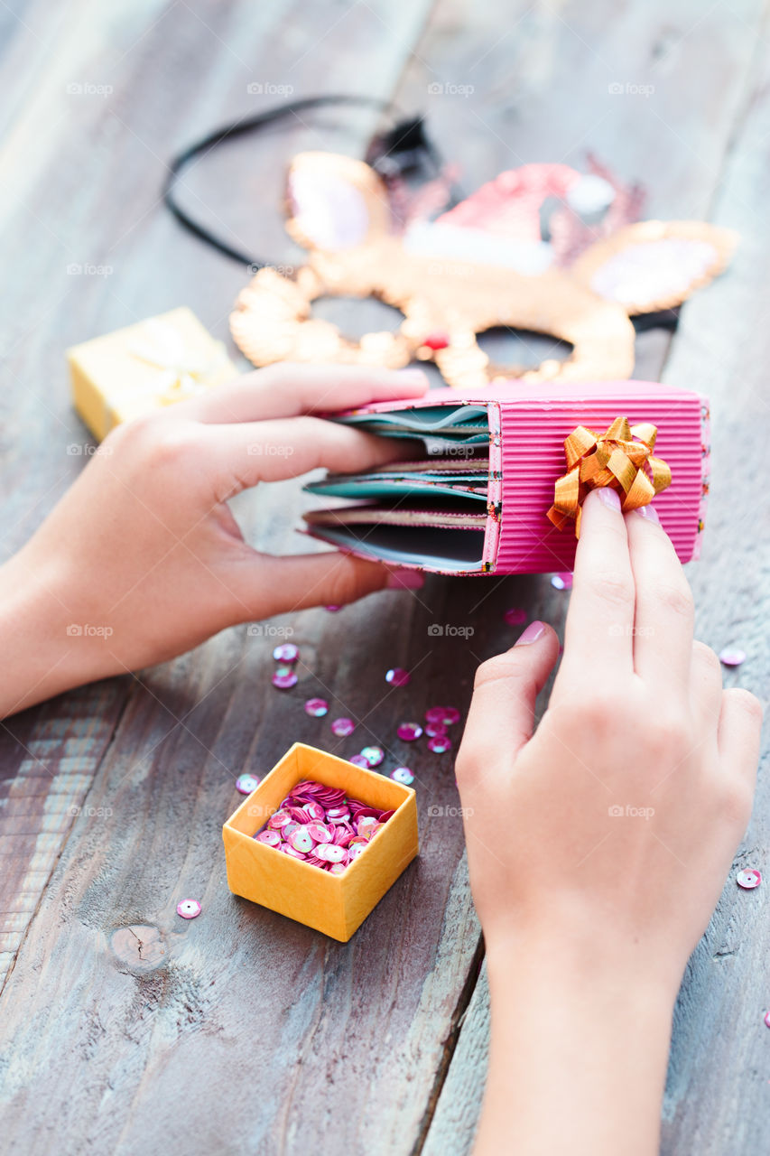 Close shot of female hands making decorations of Christmas gifts following diy ideas on wooden table