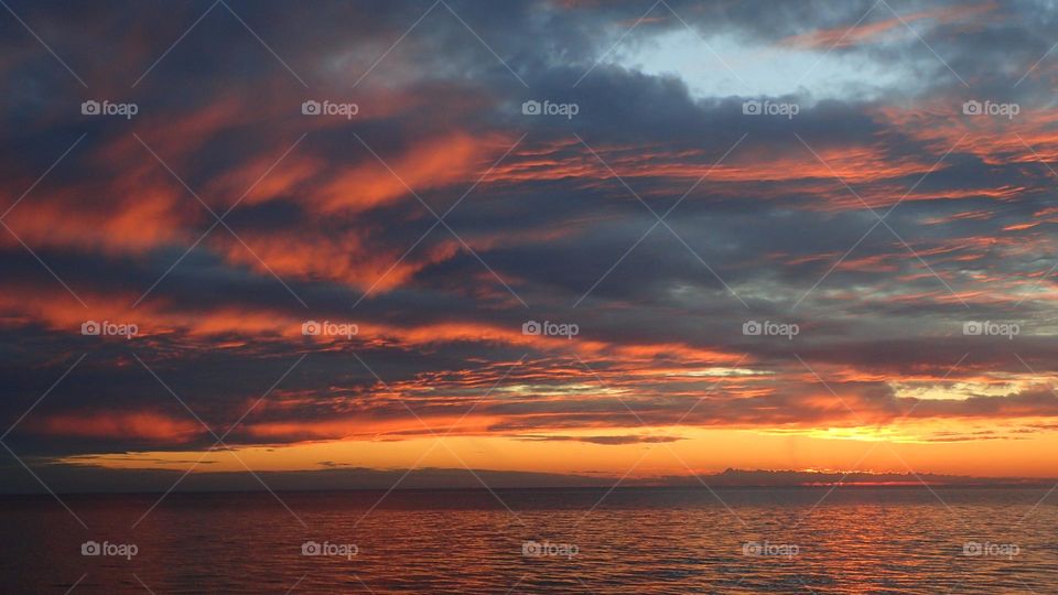 Striking fiery sunset clouds against bright golden orange horizon sky on fire rarely seen stunning beauty