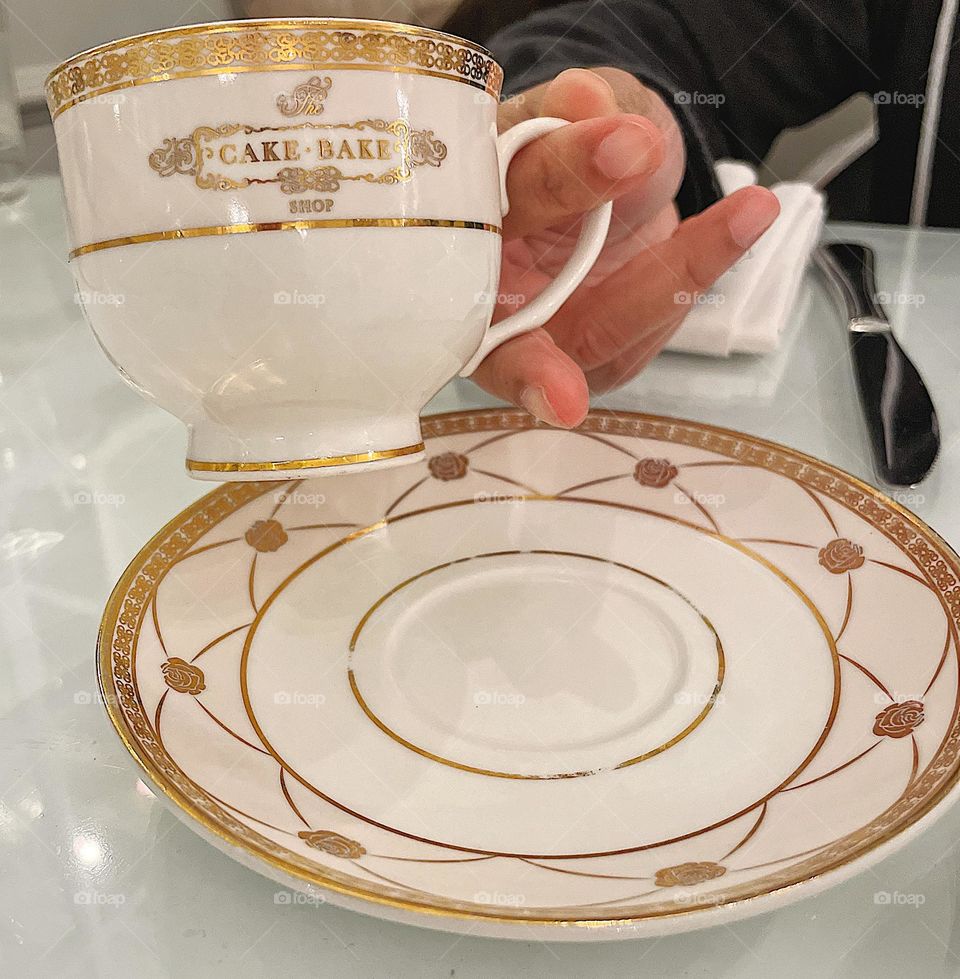 Hand holding cup, drinking lattes at a cake shop, eating cake and drinking coffee, woman’s hand holding cup, drinking rose lattes