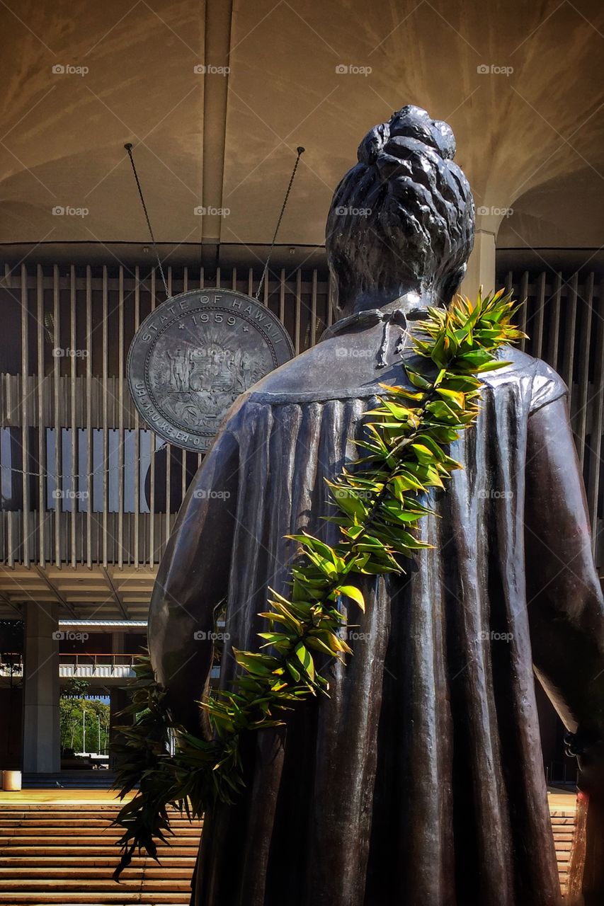 Statue of Hawaii’s last monarch, Queen Lili’uokalani, facing the Hawaii State Seal at the Hawaii State Capitol Building 