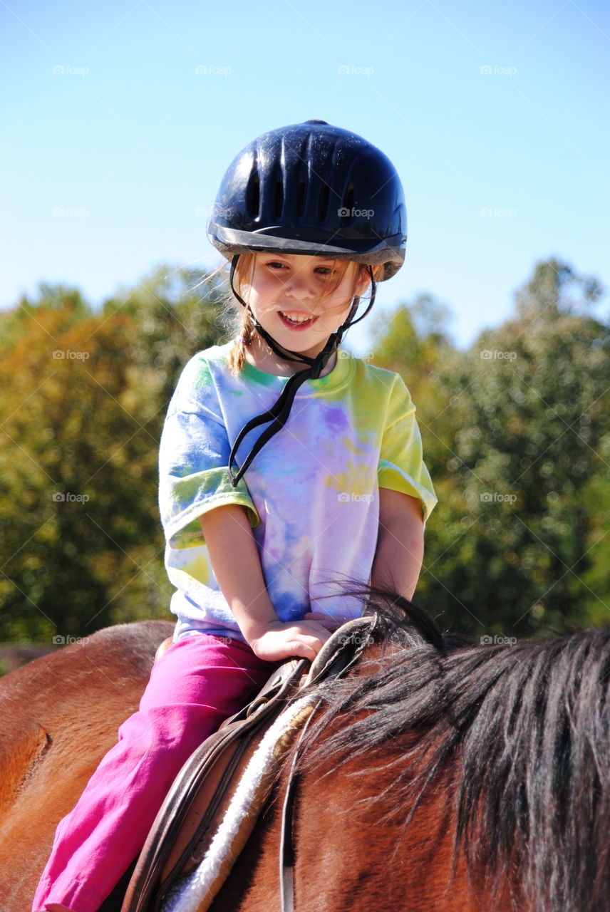 Girl riding on brown horse