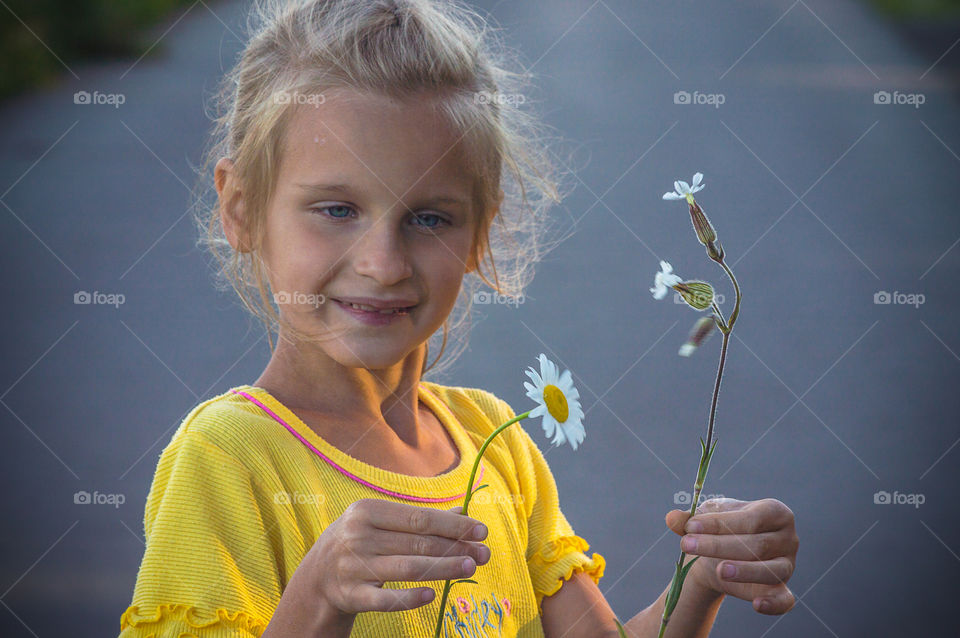 Little girl with daisies in the hands