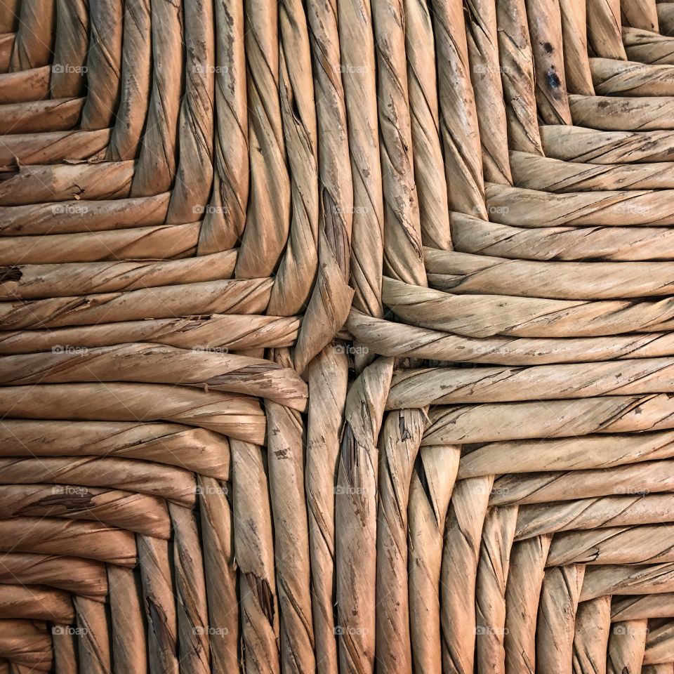 A close view of a straw/rattan seat, in a different and close perspective, creating a beautiful abstract texture.