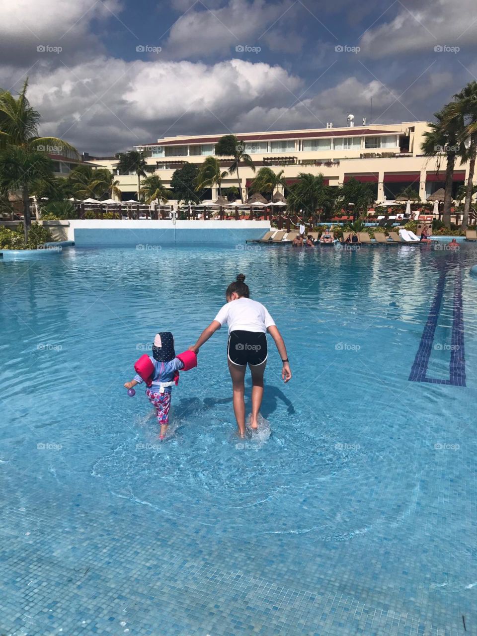 Sister and sister walking into pool in Mexico 