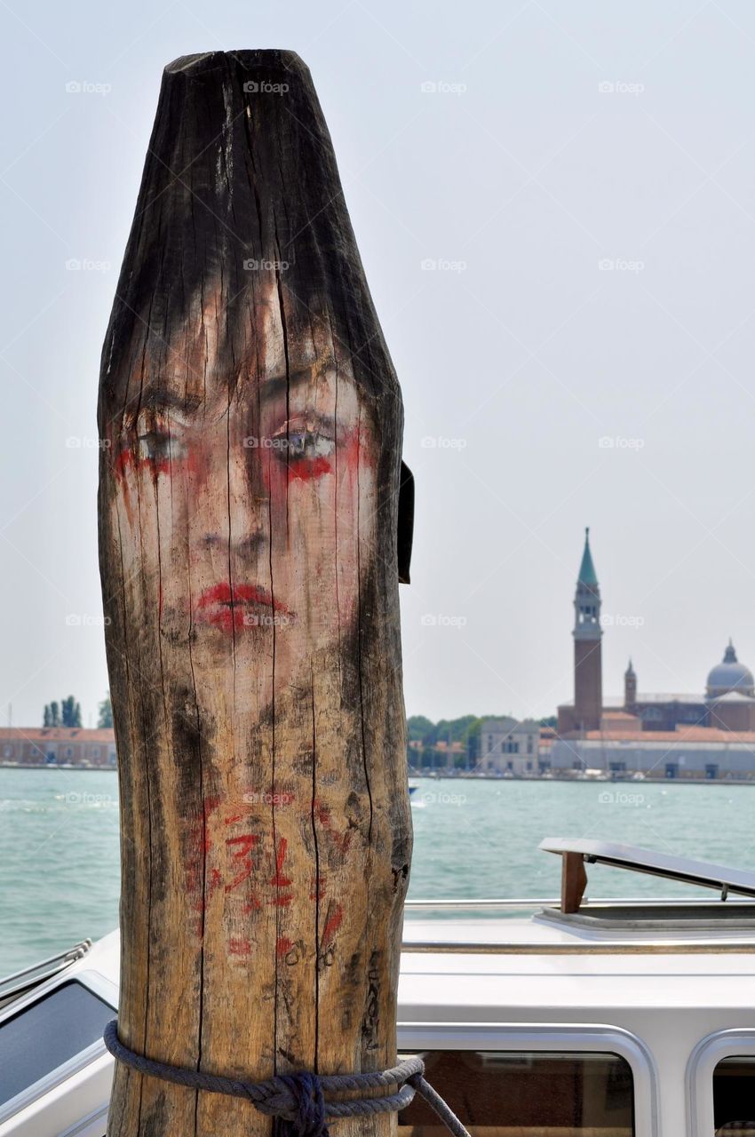  Wood painted pillar next to a pier in Venice, woman face paint on wood surface 