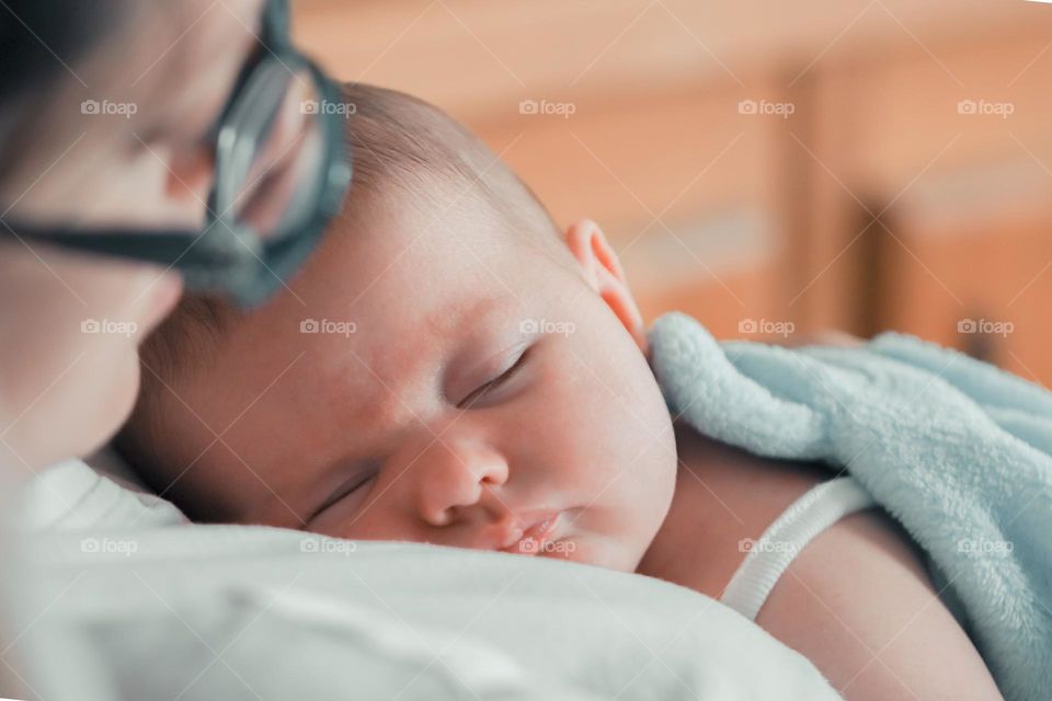 One beautiful and cute baby sweetly sleeping on his mother's chest, close-up side view. The concept of sleeping children.