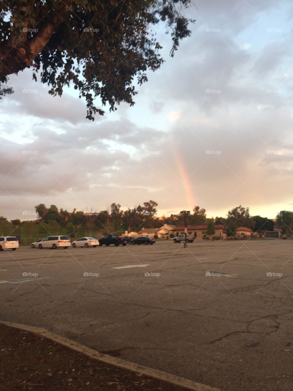 Rainbow in a parking lot. Cloudy day right after rain, sun comes out. 