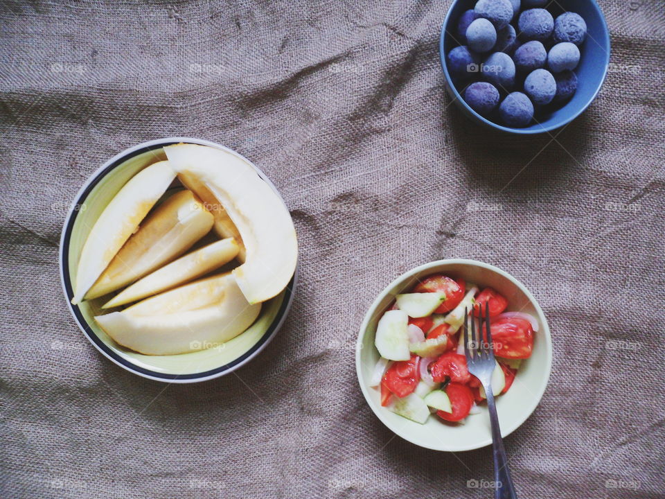 sliced ​​melon, vegetable salad, frozen plum on the table