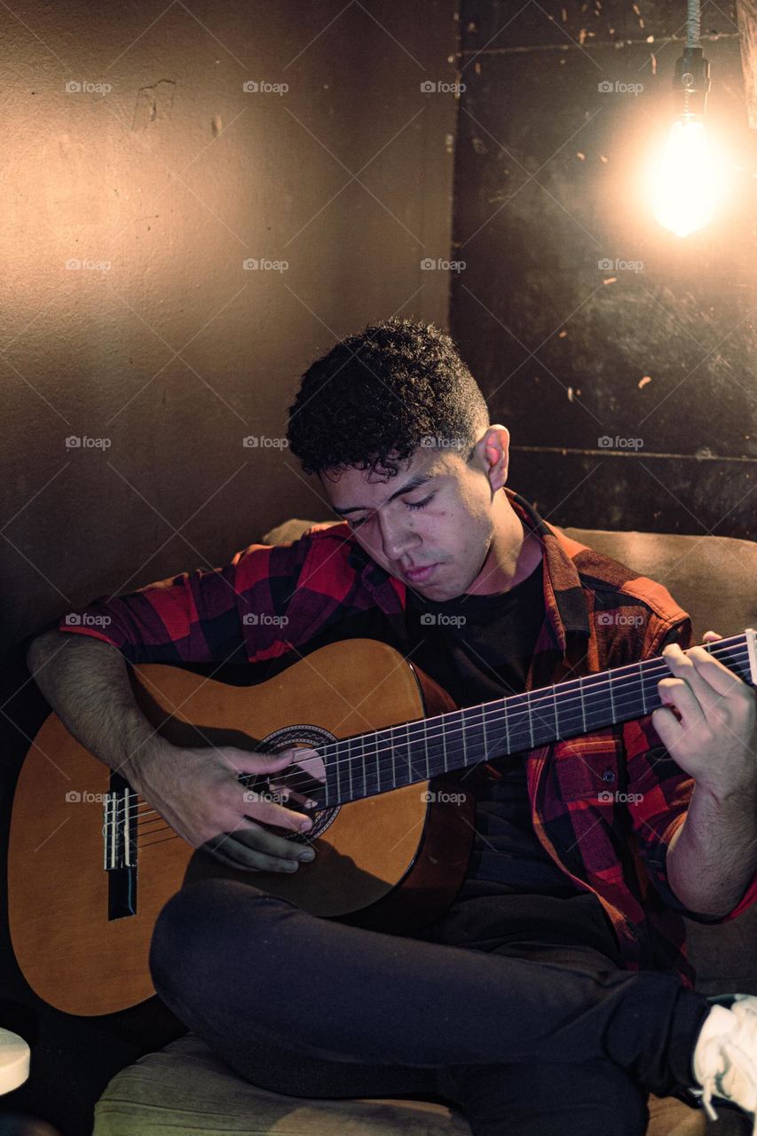 Boy enjoying playing the guitar instrument inside his room