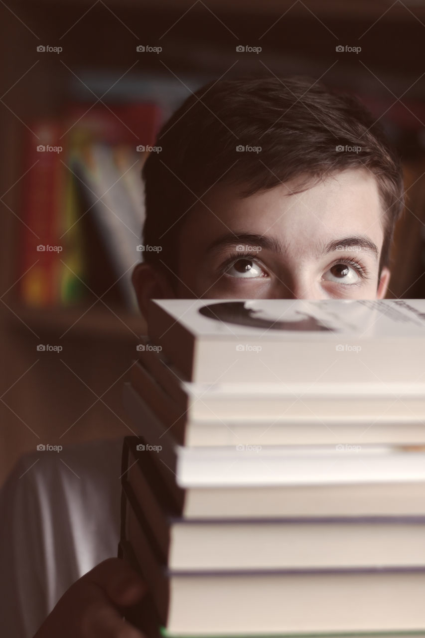 Portrait of teenage boy with stack of books.
