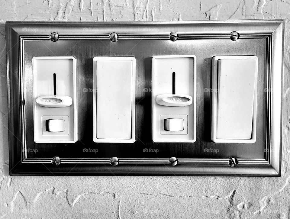A four position light switch on a wall is a perfect rectangle