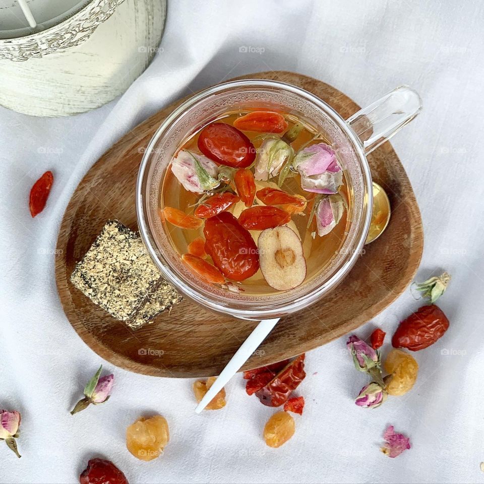 Comforting cup of ginger red date tea with rose buds , dried longan, goji berries