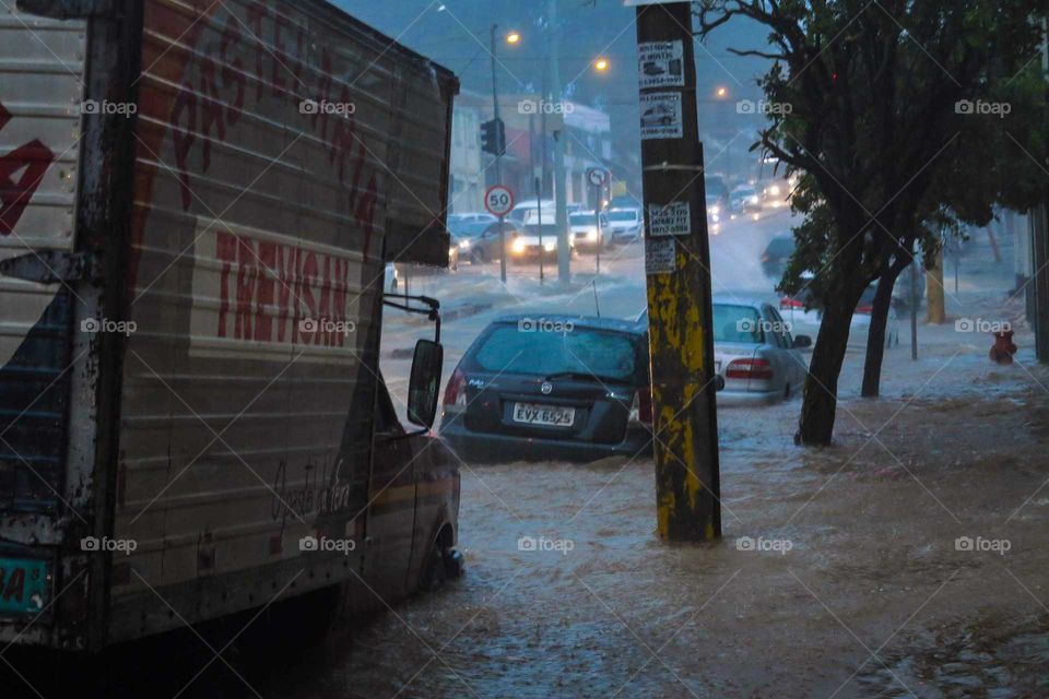 Car on a heavy rain day, on a flood, flooded street at Piracicaba, Brasil. 
Black car on the Waters of a flood in Brazil.