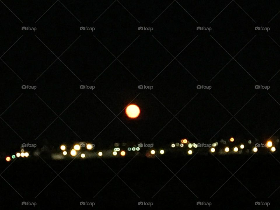 Small city lights meets bright full moon on a very dark night