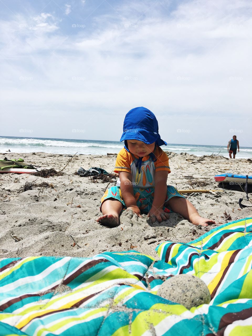 This photo captures an adorable baby playing in the sand of a California beach on a warm summer day.