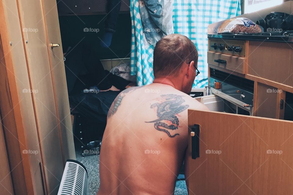 Man with tattoos inside a caravan