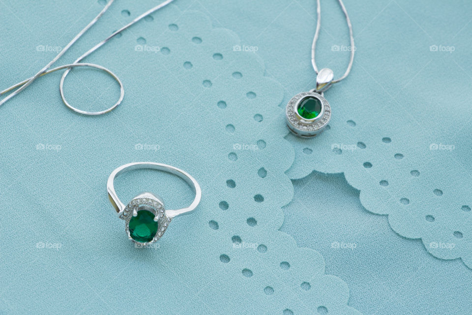 A ring and a necklace with green color gems, along with a light green blouse.