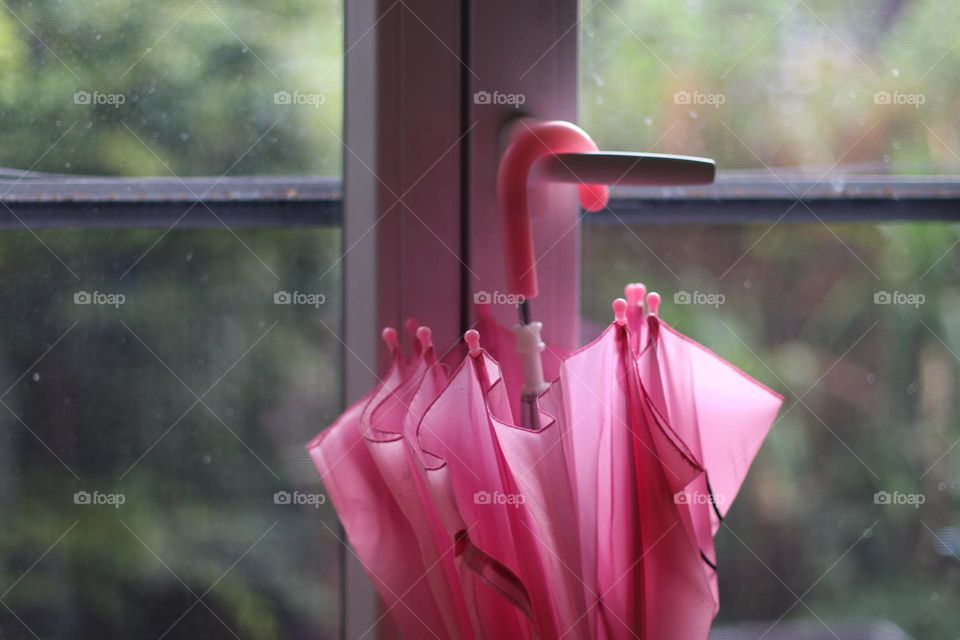 A pink umbrella hangs on the handle of a glass door
