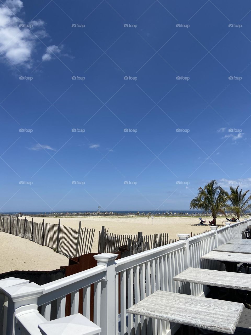 A corner of Point Pleasant Beach boardwalk with an amazing view of the beach and ocean. Please put me in the corner! Taken where the boardwalk fence meets the fence of a boardwalk eatery. The sky is blue as can be to match the ocean.