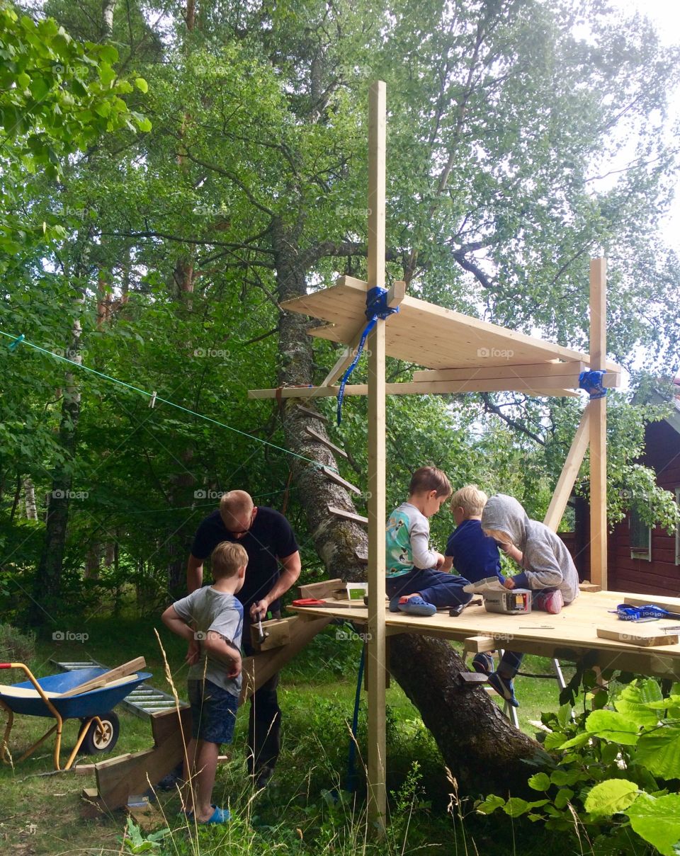 Kids and dad constructing treehouse 