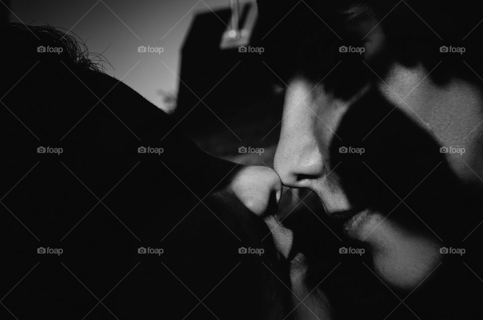 The couple of lovers touch each other nose to nose. Light and shadow. Close up portrait