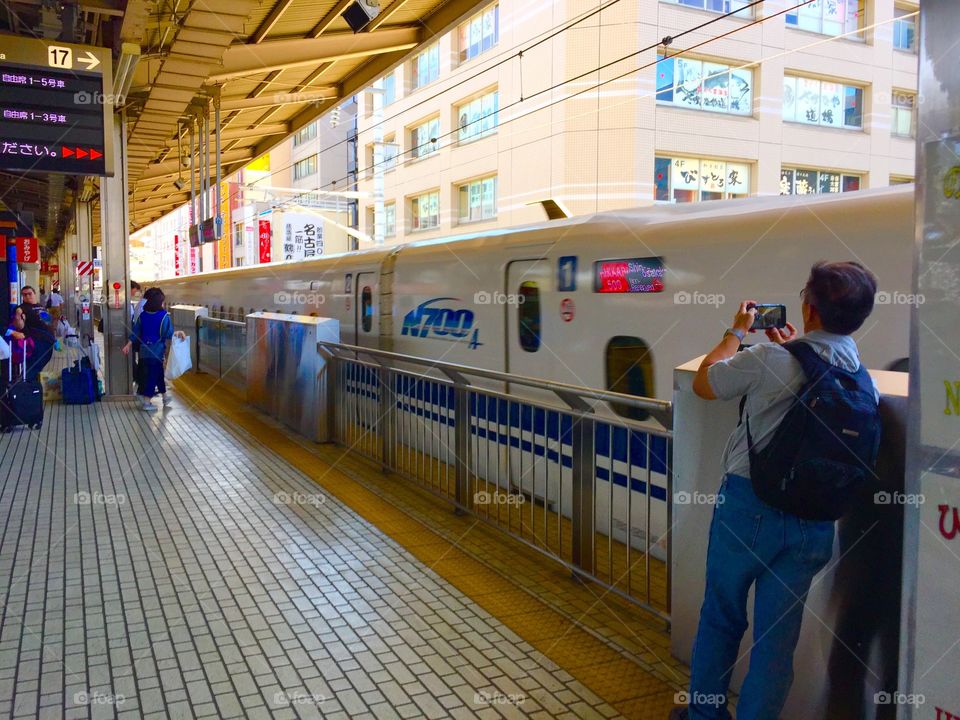 A visitor takes a photo of a train entering the train station