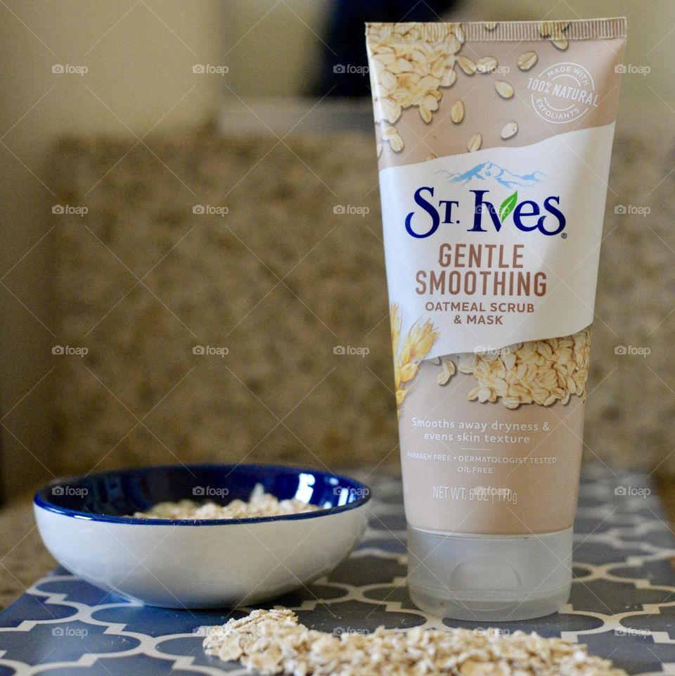  St Ives Oatmeal scrub/mask/cleanser on a bathroom counter with loose oats and a bowl 