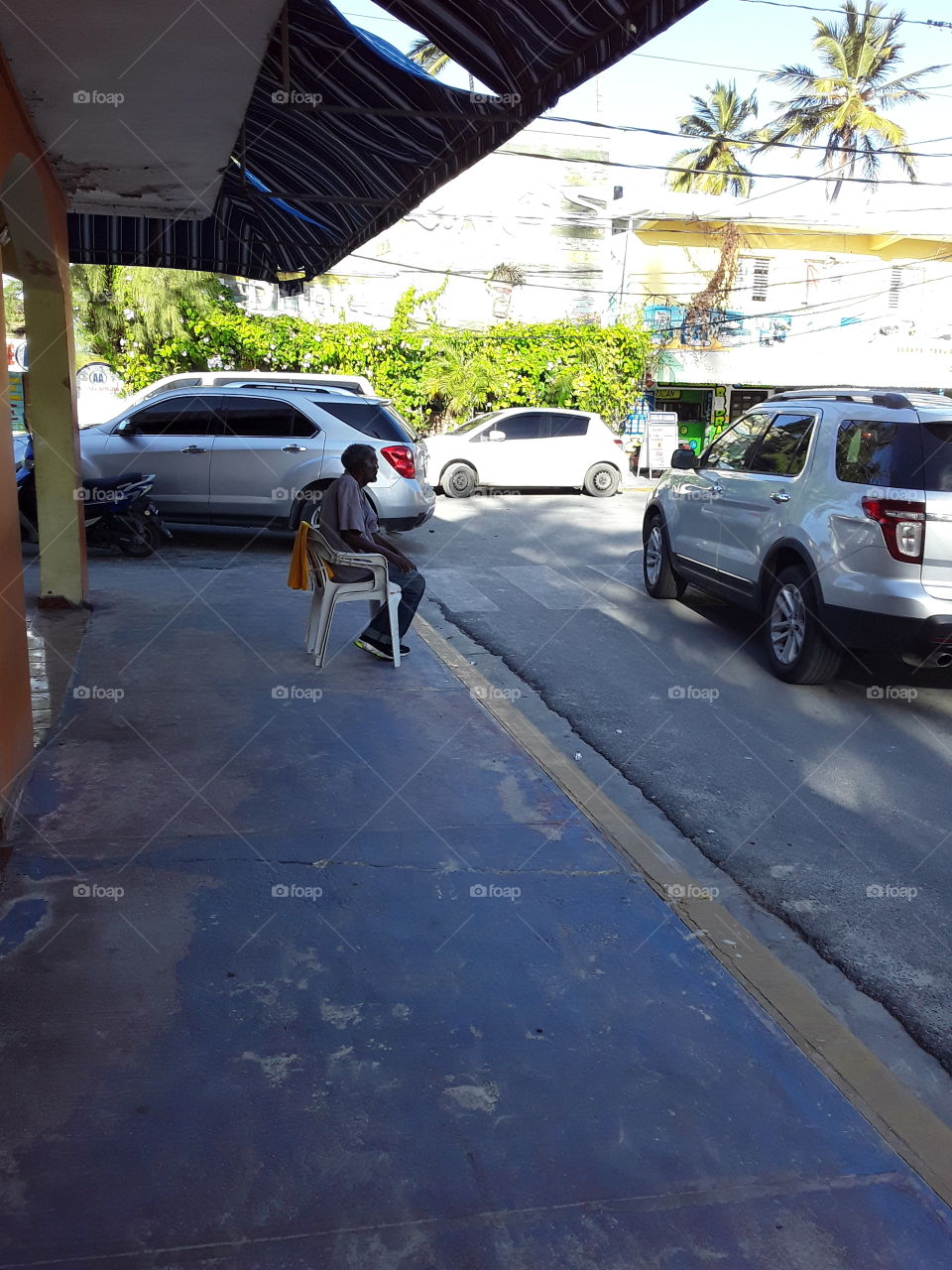 old man sitting on a plastic chair on the street in the Dominican Republic