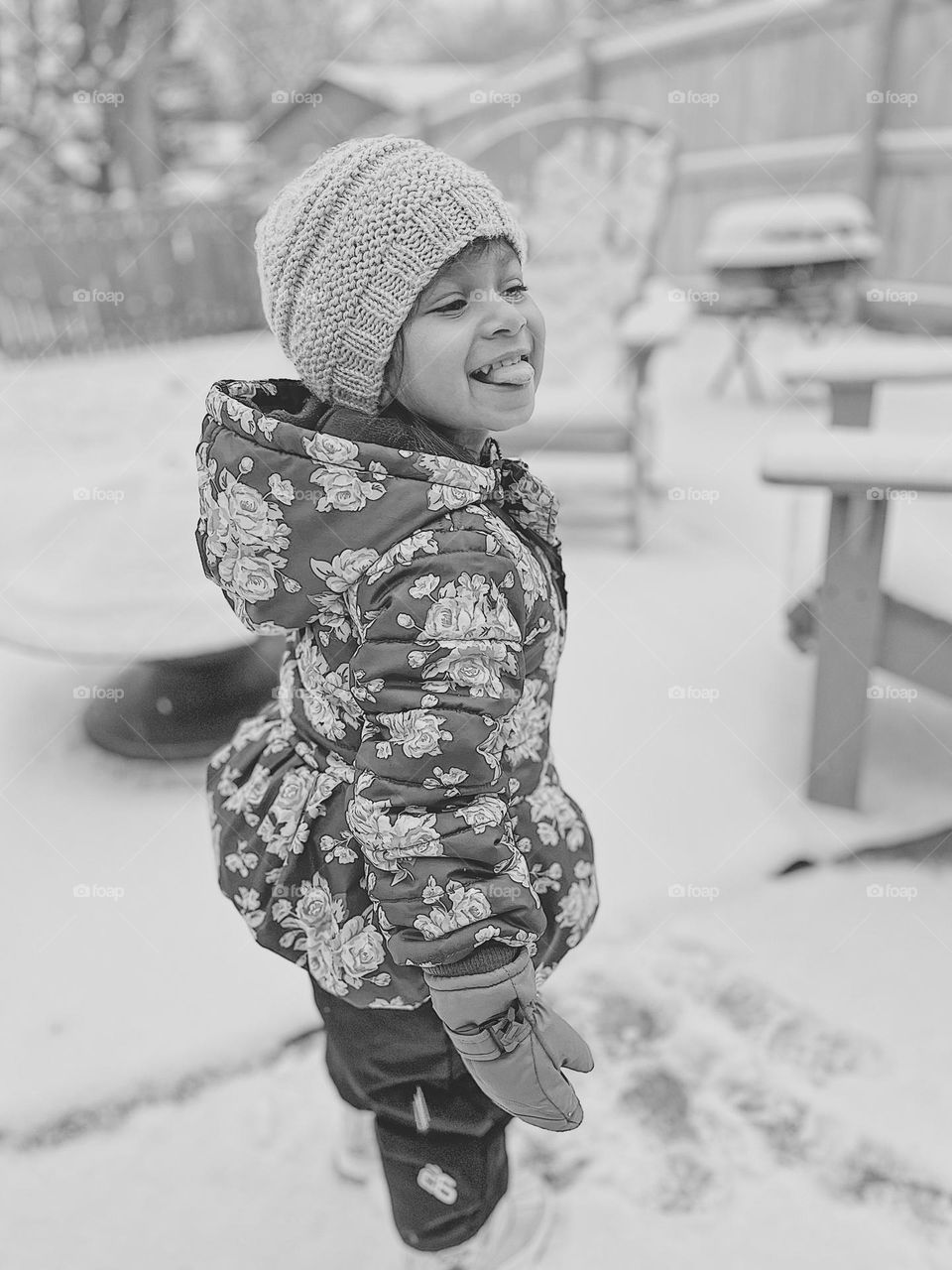 Toddler girl catches snowflakes with tongue, toddler playing in the snow, black and white portrait, snow in the Midwest, snowing in January