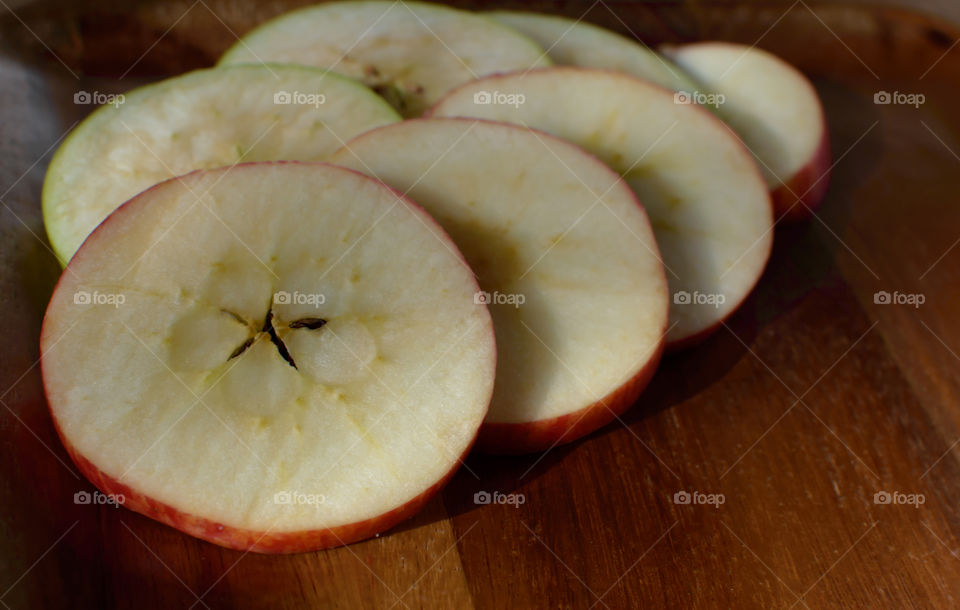 Crisp sliced red apple cross section in circle shape with star shaped seeds closeup full frame health, wellness, self-care and diet conceptual food photography background 