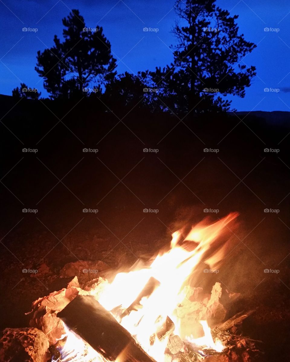 The campfire illuminates the desert bacground.