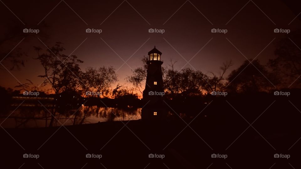 Night is near. Peaceful illuminating backlit colours Twilight hanging on as long as possible. Lighthouse in fore ground is illuminated for peaceful transition throughout the cold night ahead. 