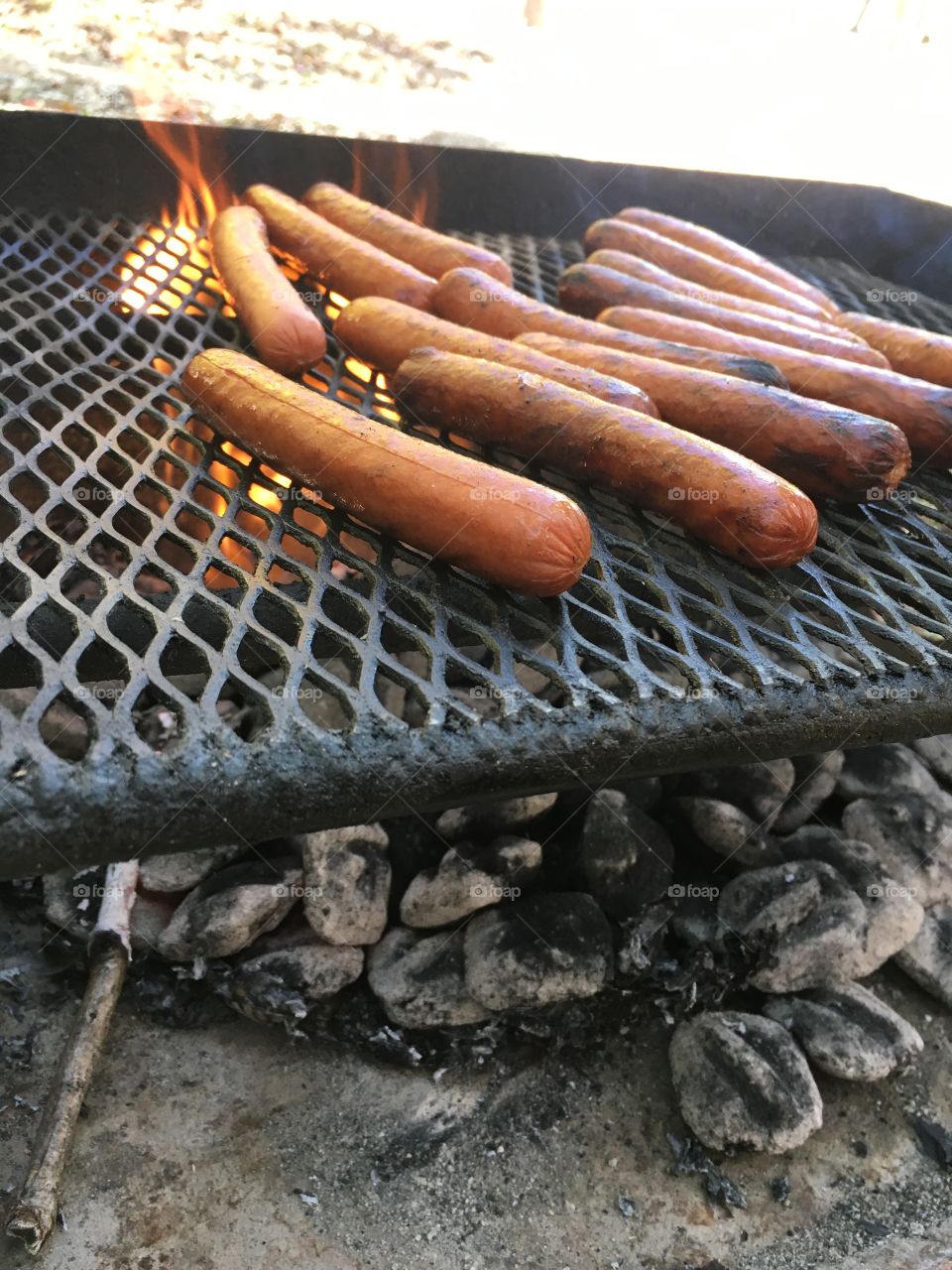 Grilling hotdog on charcoal grill