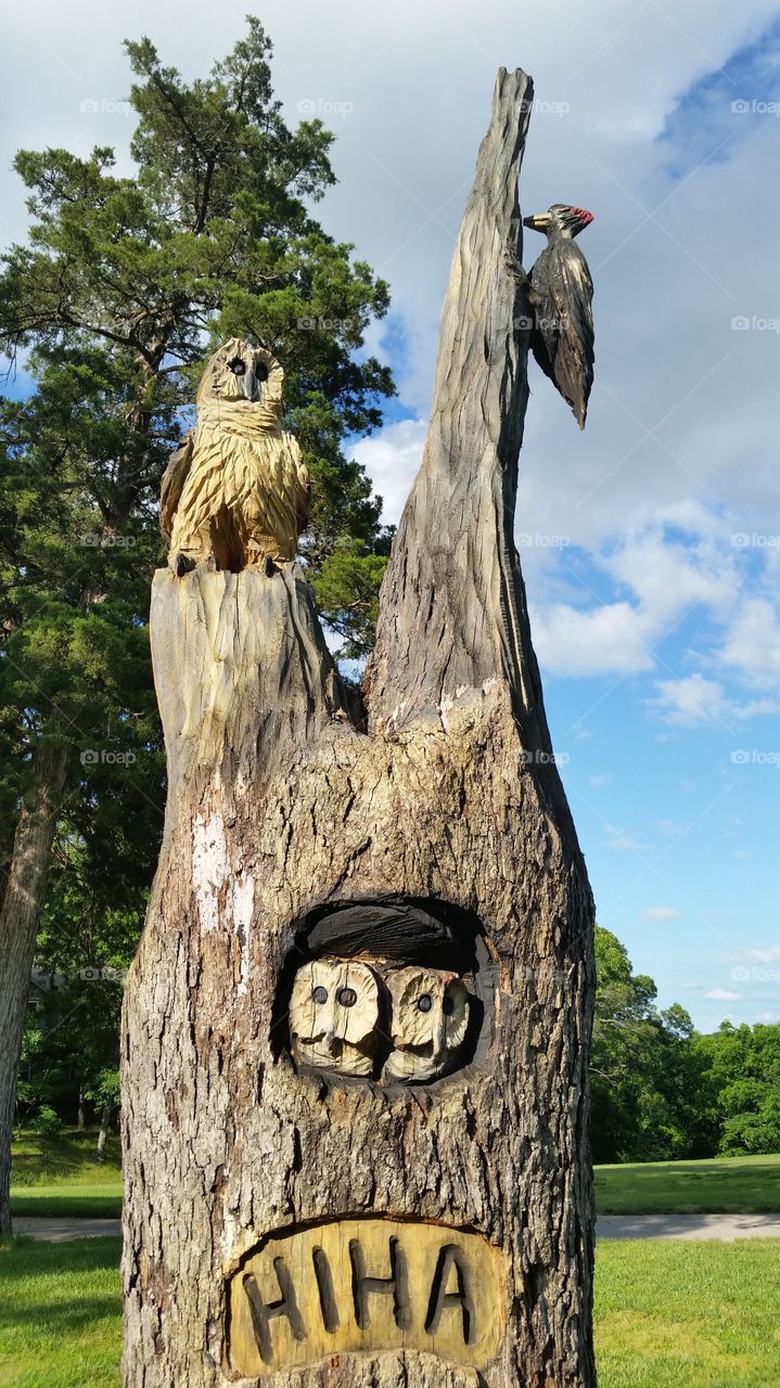 Tree Art. Woodcarving of owl and woodpecker on tree stump