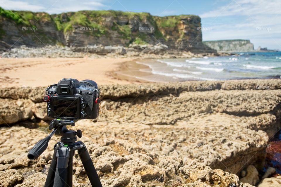 Camera on a tripod pointing at a beautiful beach