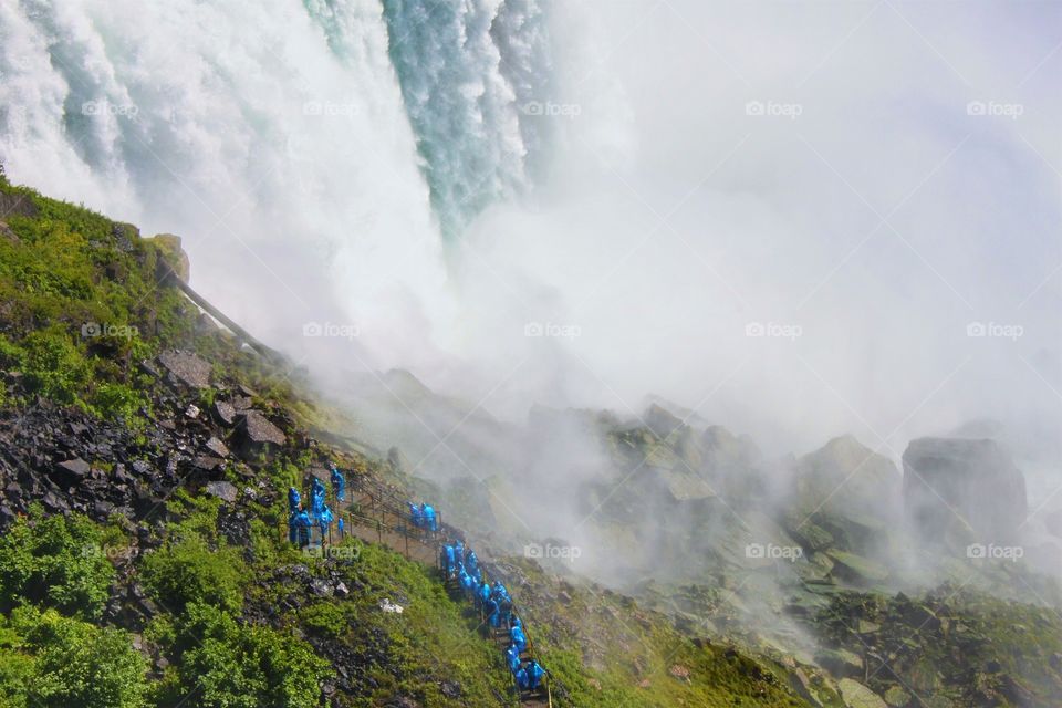 people wearing blue rain coat enjoying under Niagara falls New York