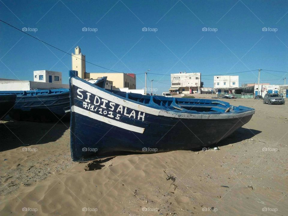 Alone blue boat on a sand.