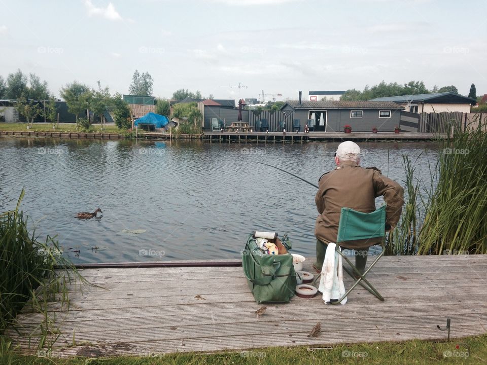 Old man enjoy fishing beside riverbank at Kinderjidk, Holland 