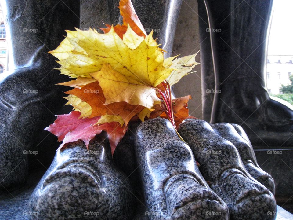 part of a giant granite statue of Atlanta his huge foot with toes and a bouquet of autumn leaves