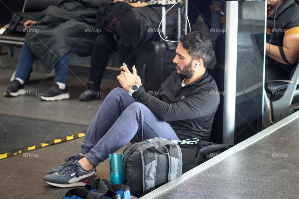 Young man is the airport using his phone