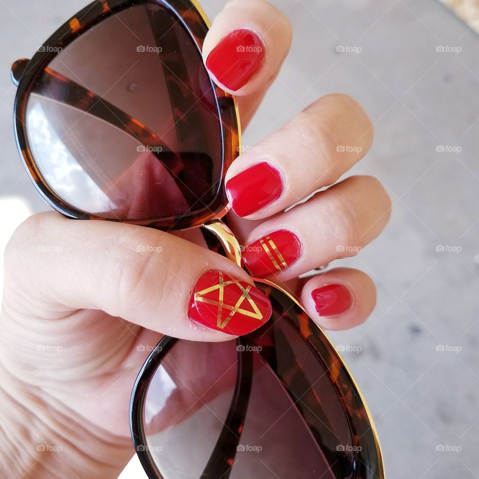 red and gold mani with sunglasses