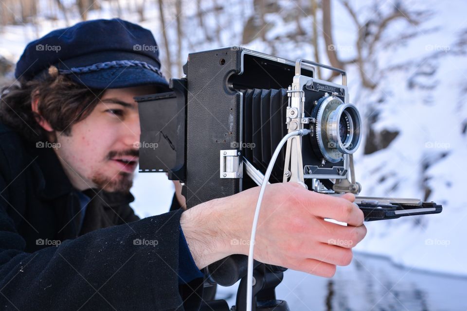 A man uses the old fashion photography equipment of a film camera to capture his image 