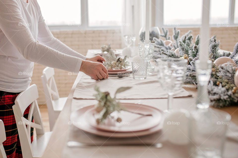 man sets a beautiful decorated winter table for a festive dinner.  Merry Christmas and Happy New Year.