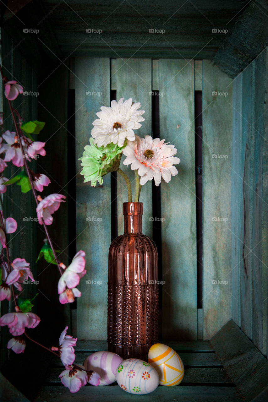 Easter eggs and spring flowers in a vintage vase against a wooden background 