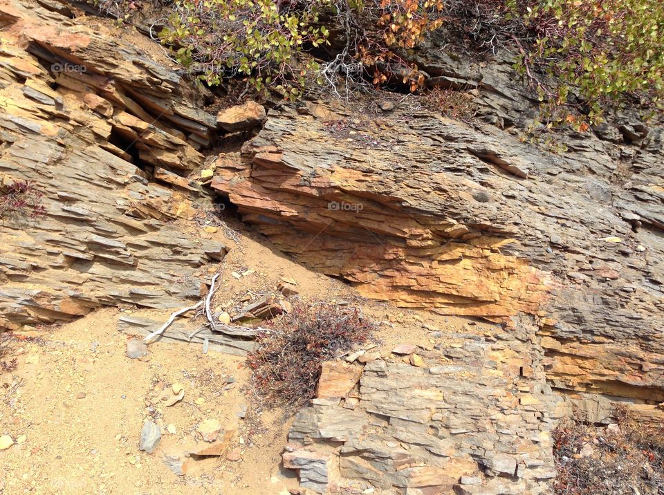 Rough layers of beautiful reddish brown rock on a hillside in Central Oregon on a sunny day. 