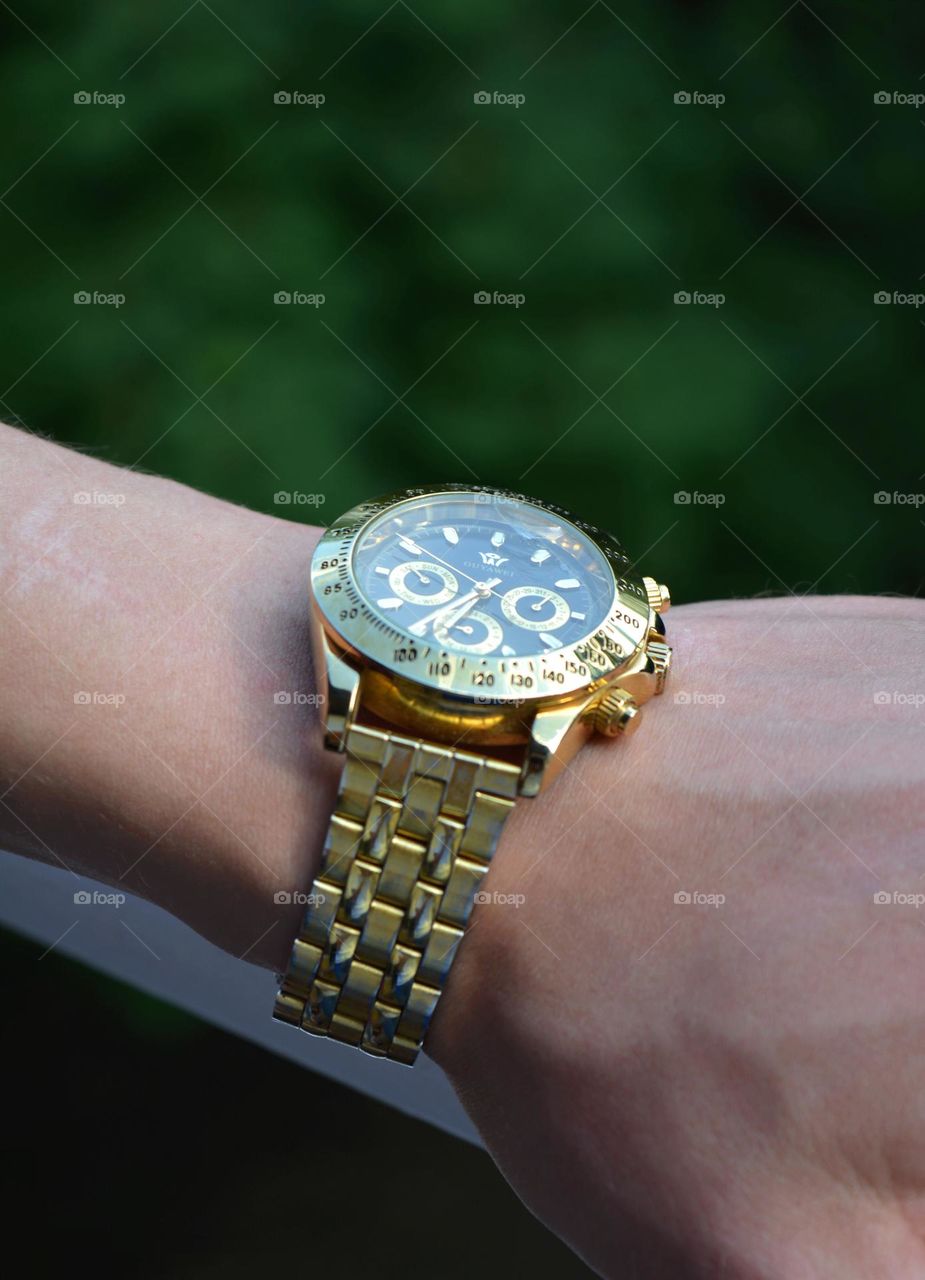 golden clock on a male hand and beautiful round structure