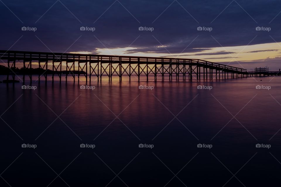 A pier backlit by the sunrise stretches out over the Neuse River estuary at Camp Seagull in North Carolina. 