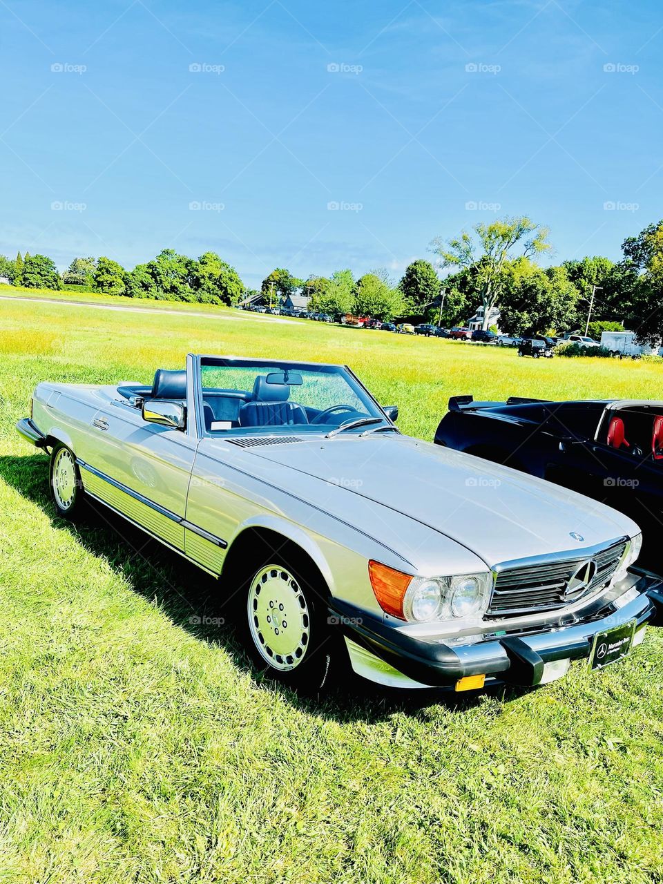 Vintage classic elegant silver Mercedes Benz convertible parked at a social gathering uniting owners and enthusiasts of classic cars. 