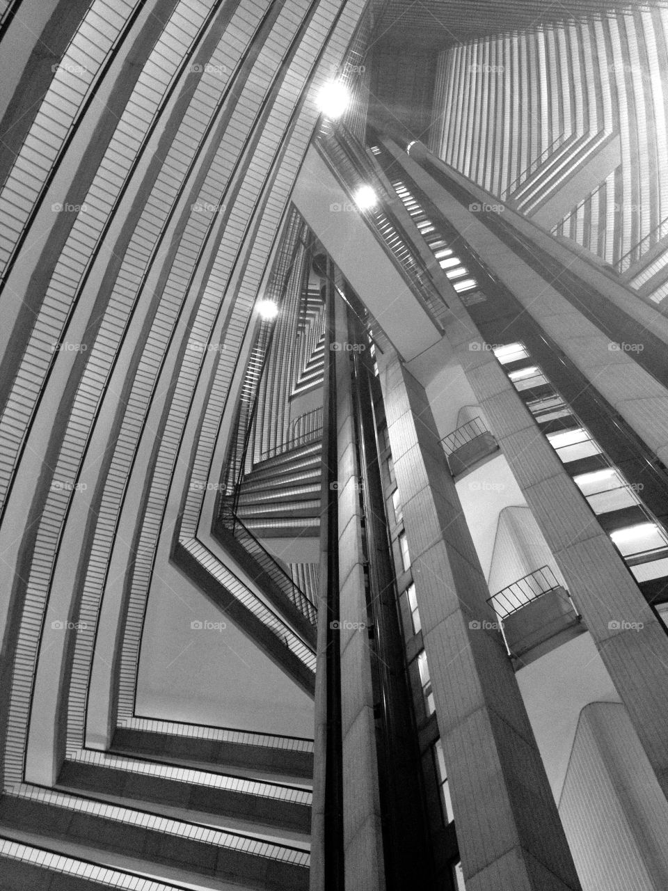Black and white interesting architectural interior of a hotel. Pleasing angles and perspectives looking up through the open space and many floors facing the interior.